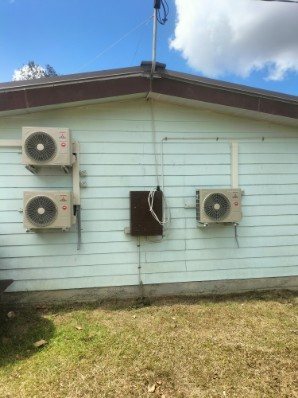 Three outdoor units mounted along a weatherboard wall