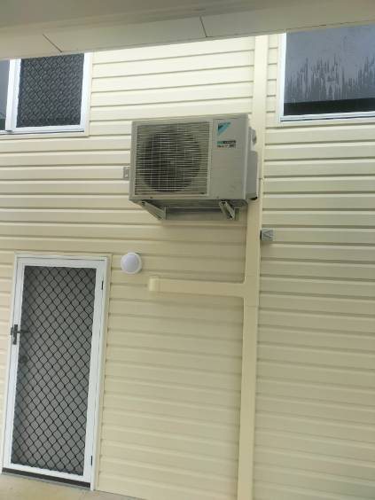 Daikin outdoor unit on brackets above a screen door